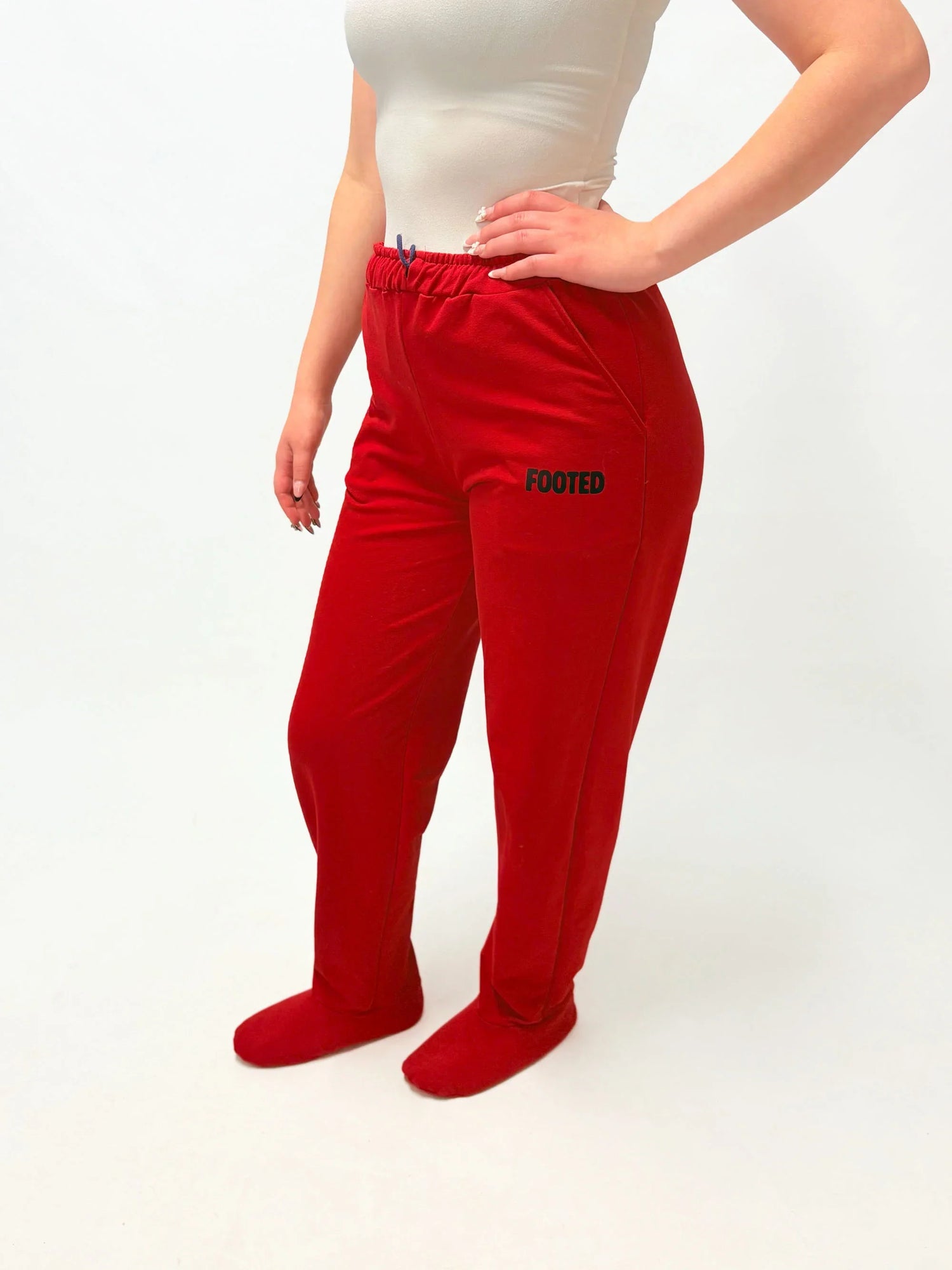 Red FOOTED pants with footed design, modeled with a beige top on white background.
