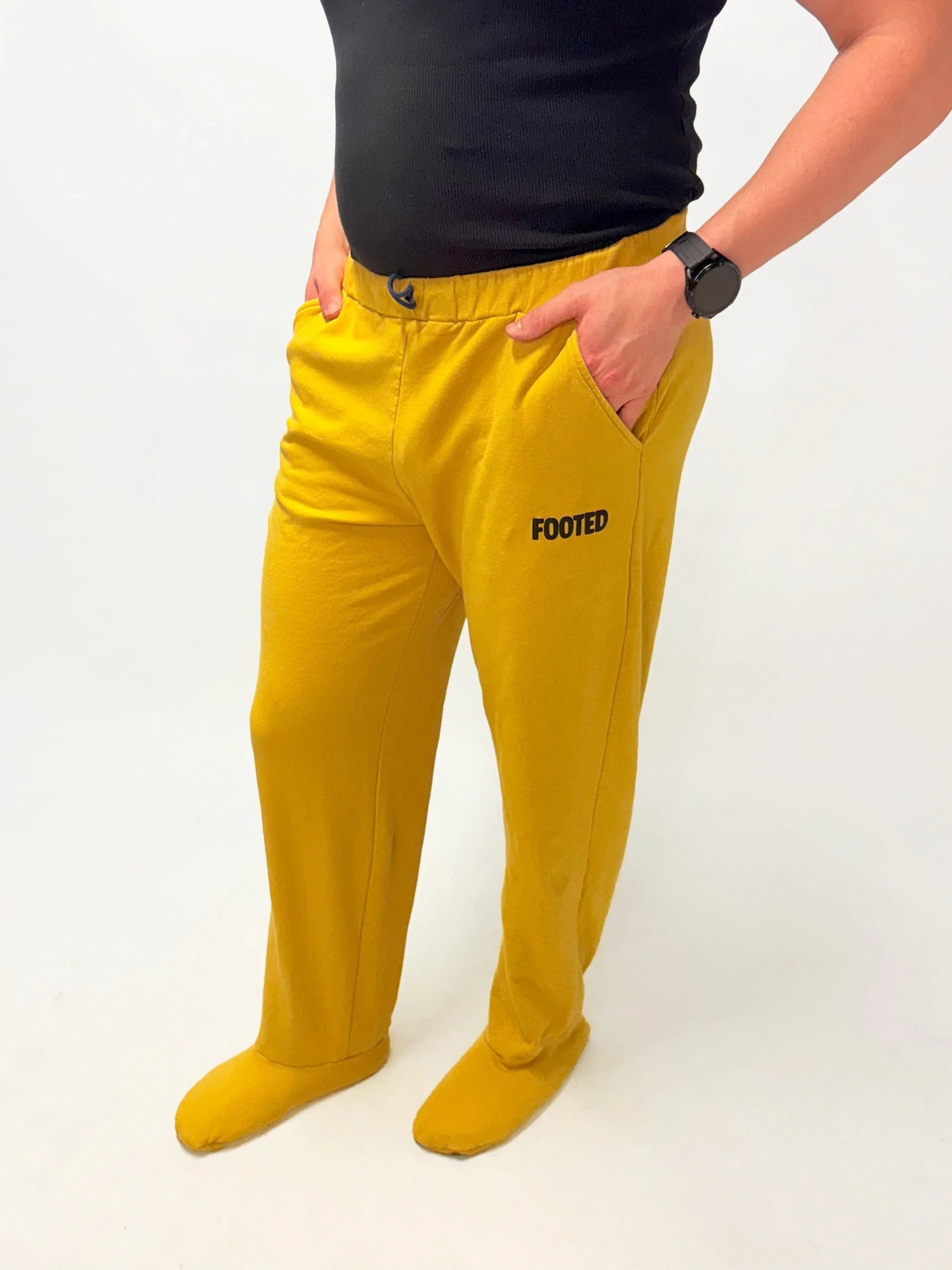 Yellow FOOTED pants with footed design, modeled with a black top on white background.