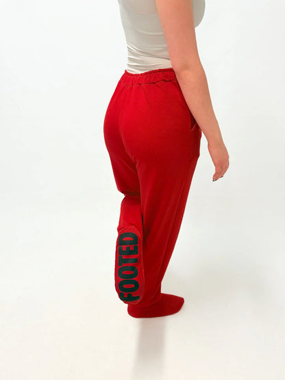 Model wearing red FOOTED pants viewed from the back on a white background.