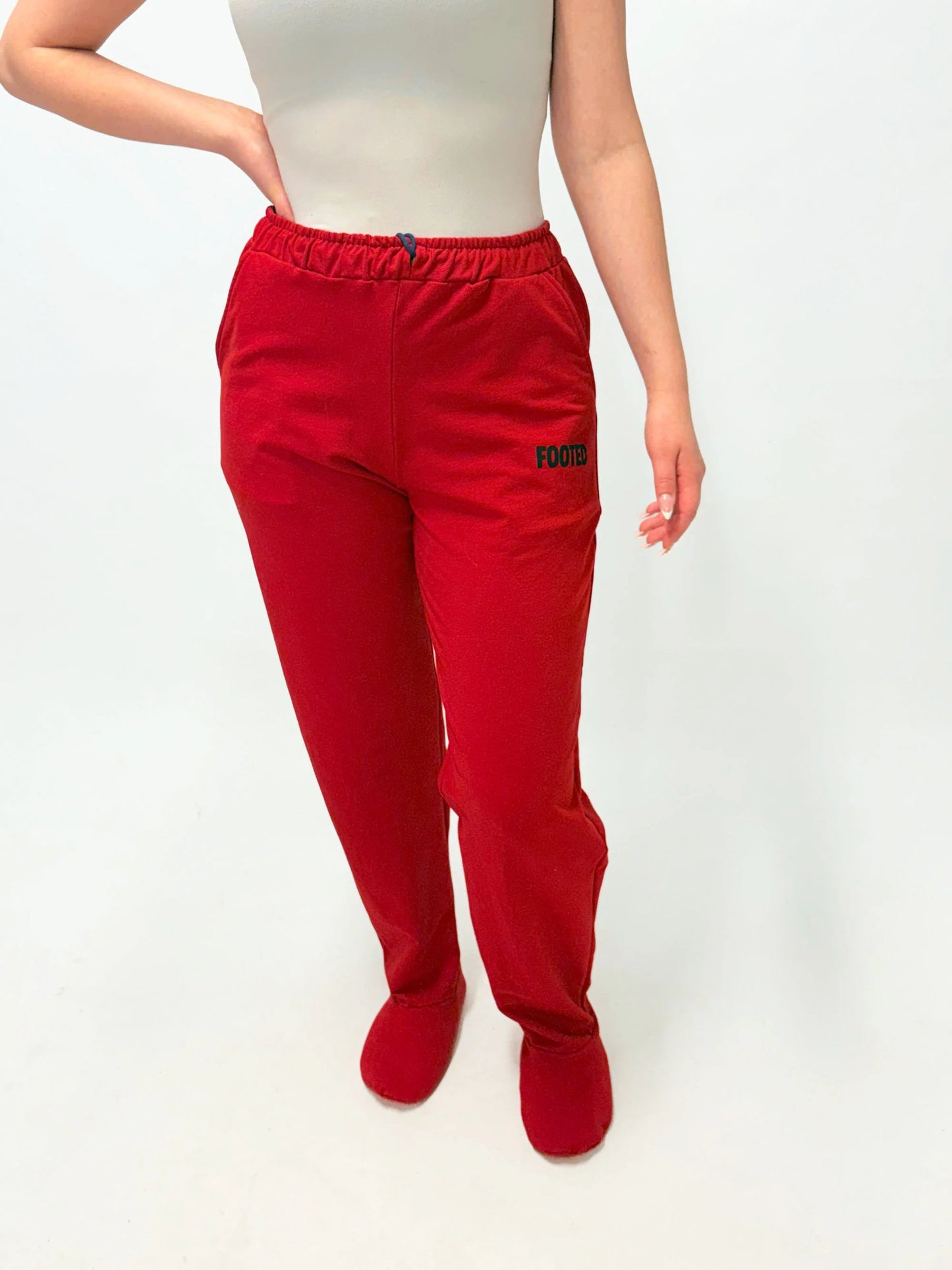 Model wearing red FOOTED pants viewed from the front on a white background.