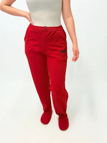 Model wearing red FOOTED pants viewed from the front on a white background.