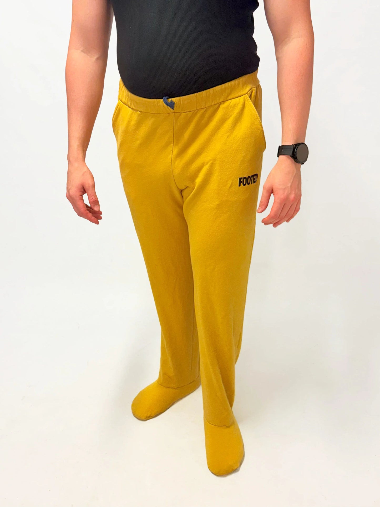 Model wearing yellow FOOTED pants viewed from the front on a white background.