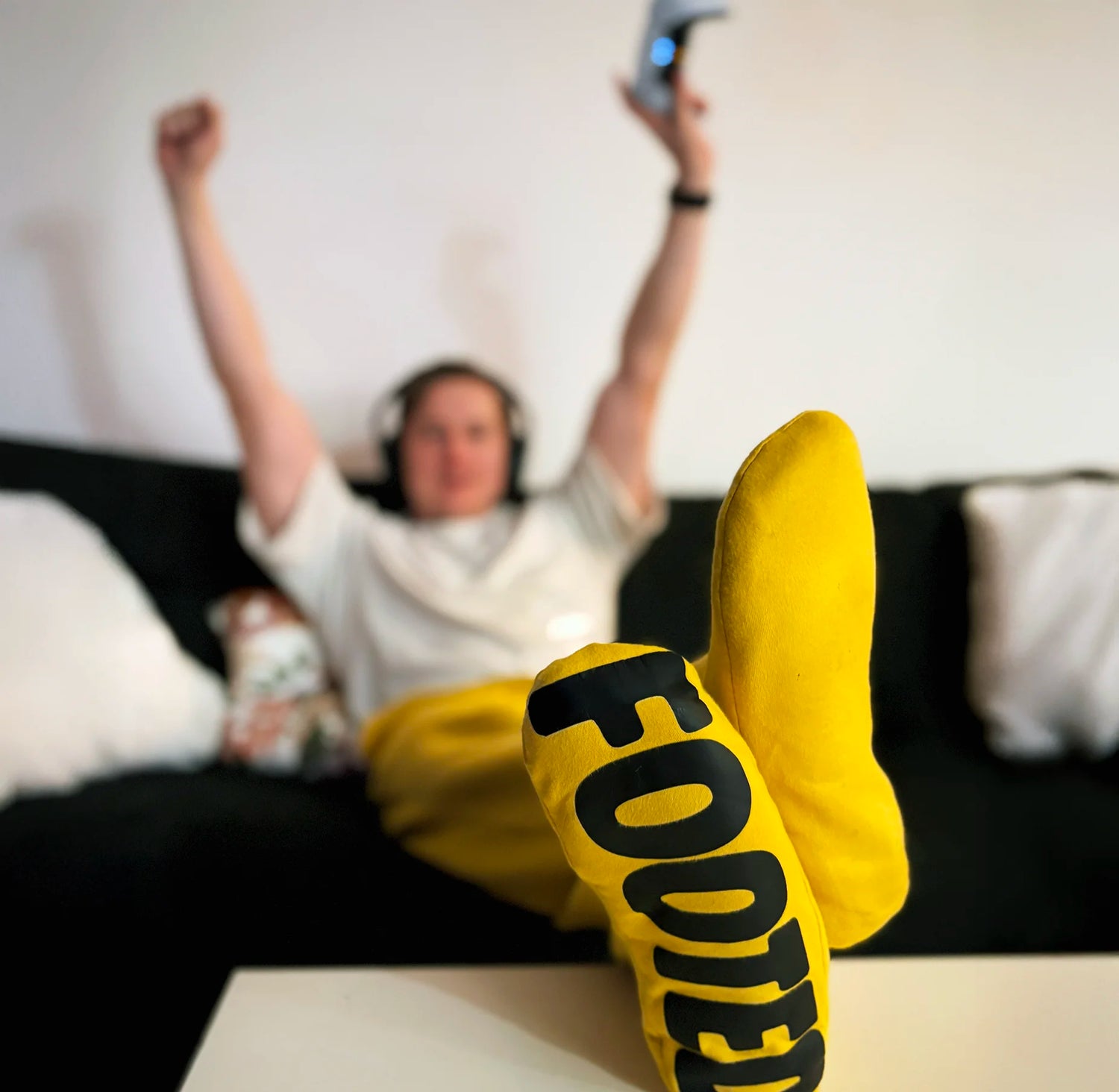 Person relaxing on a couch wearing yellow FOOTED pants, showing the footed design in a cozy home setting.